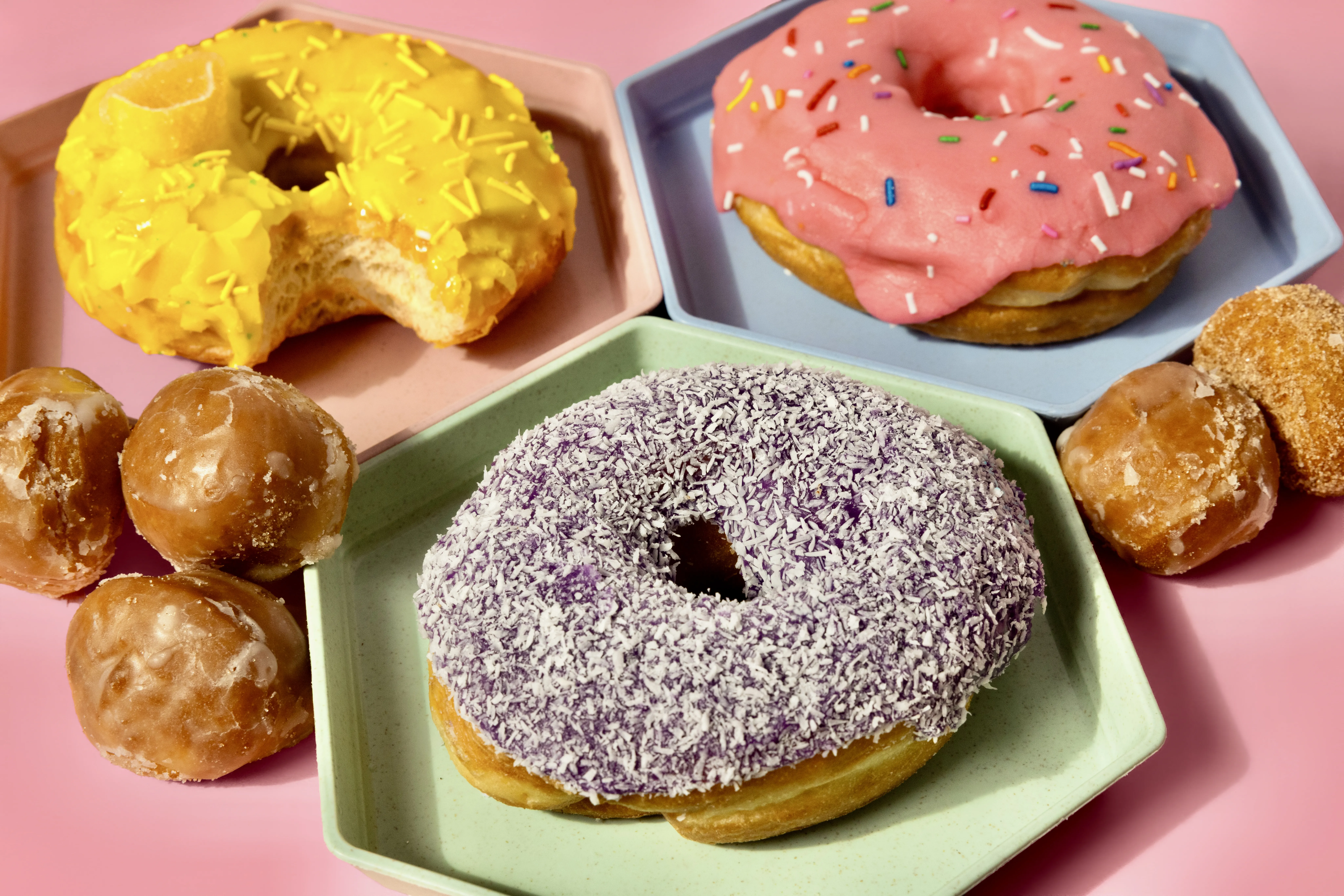 A trio of donuts on a plate, one has a bite out of it.