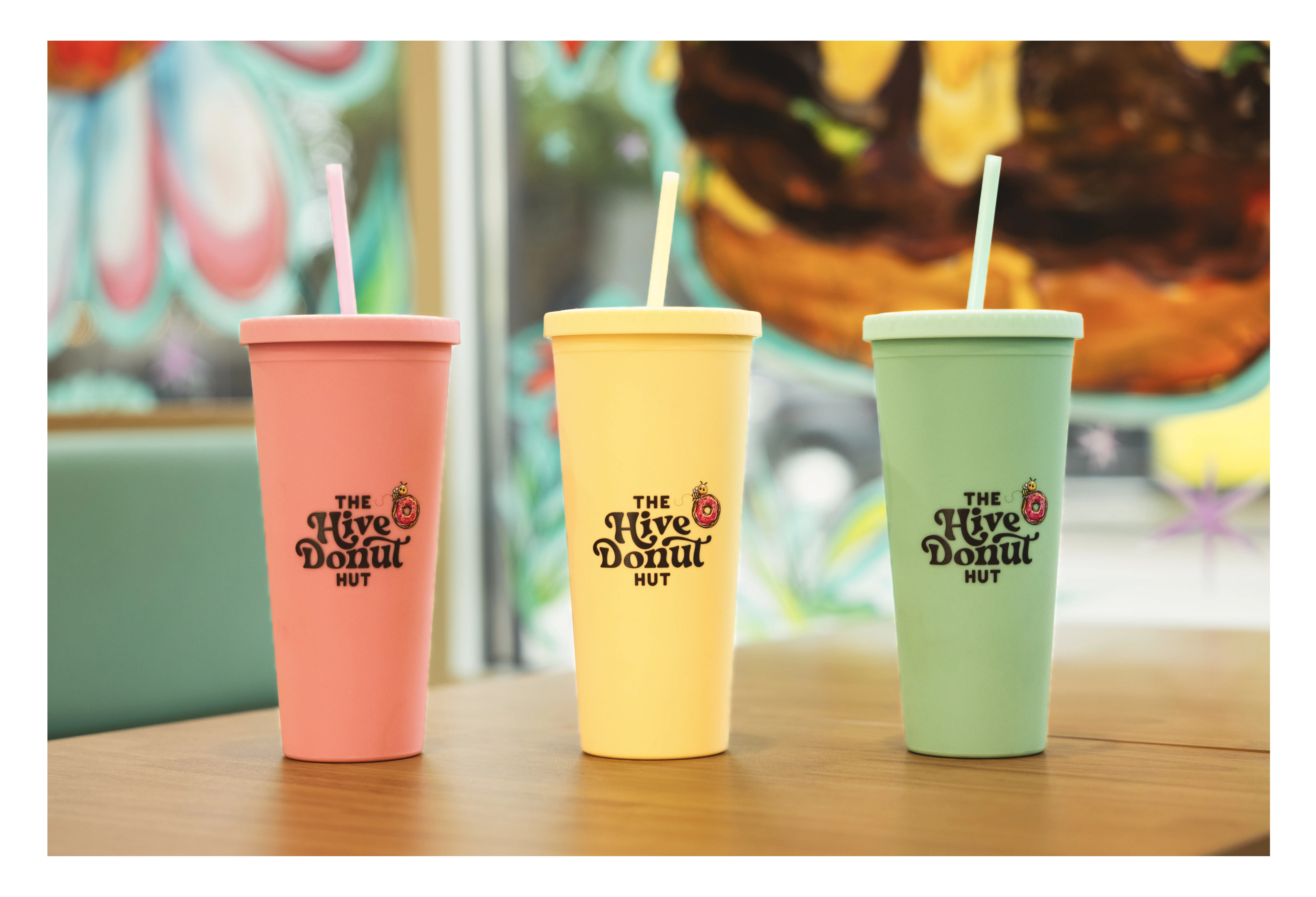 Two Hive Donut Hut travel cups of coffee on the counter, lidded and ready to go.